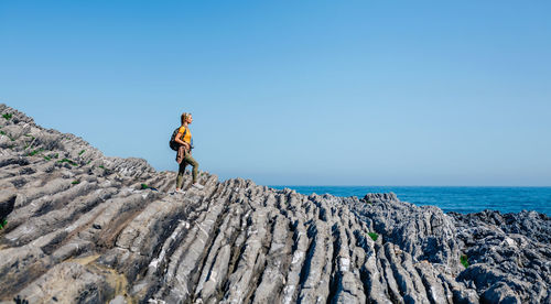 Woman with backpack walking through flysch rock landscape