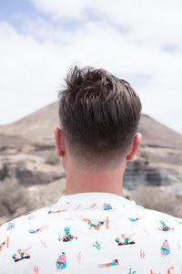 Rear view of man with arms raised against sky