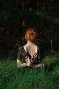 Rear view of woman sitting on field