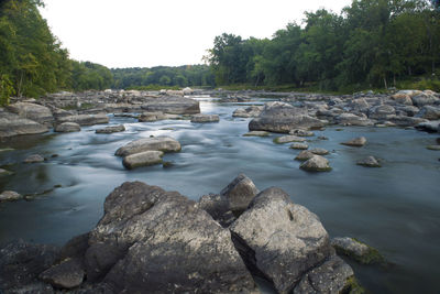 Rocks in river against sky