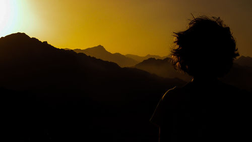 Silhouette woman standing on mountain against clear sky during sunset