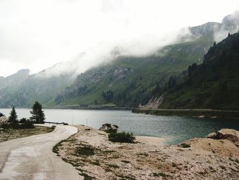 Scenic view of river by mountains against sky