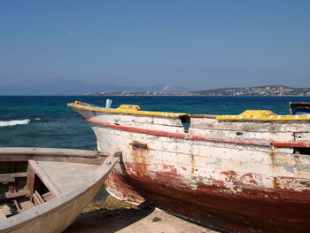 Boat moored on beach against clear blue sky