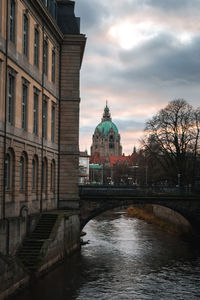 Bridge over river amidst buildings against sky in city