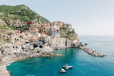 Aerial view of townscape by sea against sky