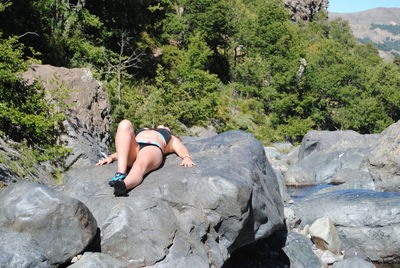 Full length of young woman relaxing on rock