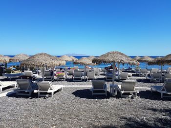 Chairs on beach against clear blue sky