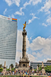 Statue in city against cloudy sky