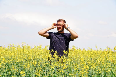 Man standing amidst yellow flowers on oilseed rape field