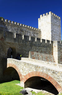 Low angle view of arch bridge against clear blue sky