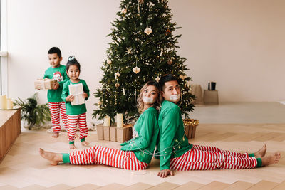 Children tied their parents with rope.  family is having fun and playing christmas holiday at home