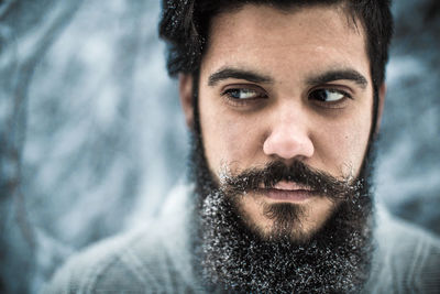 Close-up of serious young bearded man during winter