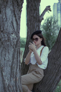 Woman sitting on tree trunk