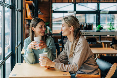 Friends using smart phone while sitting at restaurant