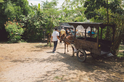 Man with horsedrawn walking on dirt road