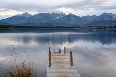 Wooden posts in lake against sky