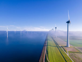 Wind turbines on field against blue sky