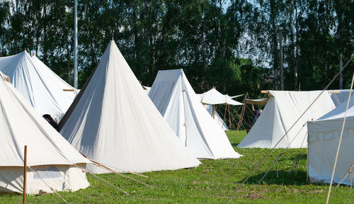 Row of tent on field against trees