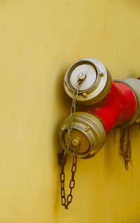 Close-up of chain hanging against yellow wall