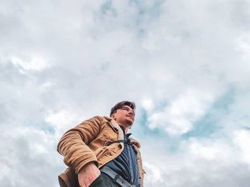 Low angle view of man standing against cloudy sky