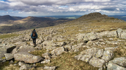 Rear view of man standing on rock against sky