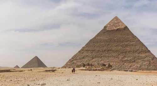 People riding camels against pyramid