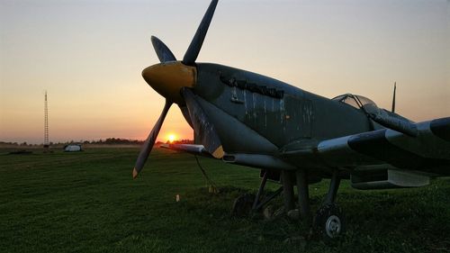 Airplane on runway against sky during sunset