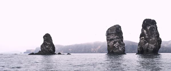 Rock formations in sea against clear sky