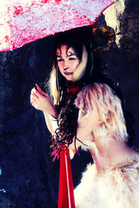 Female model in costume holding umbrella while standing outdoors