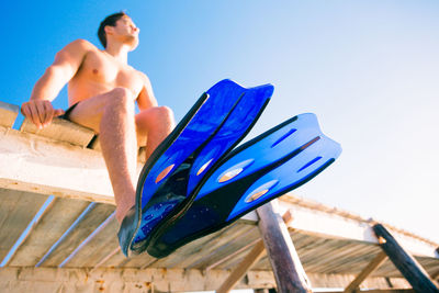 Low angle view of shirtless man against blue sky