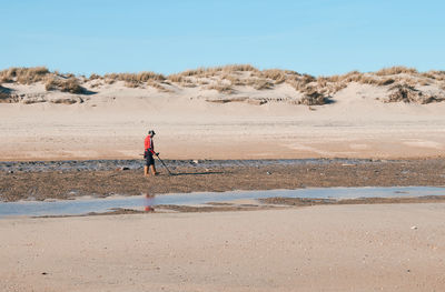 Man walking on beach against sky