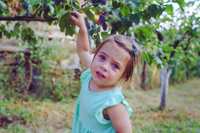 Portrait of cute girl standing by tree