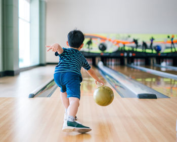 Rear view of boy playing bowling ball