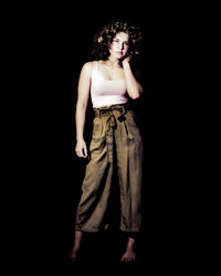 Woman looking away while standing against black background