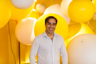 Portrait of smiling young man standing at balloons