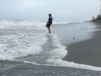 Side view of man standing on shore against clear sky