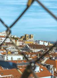 High angle view of buildings seen through chainlink fence