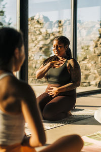 Smiling woman practicing breathing exercise in yoga class at retreat center