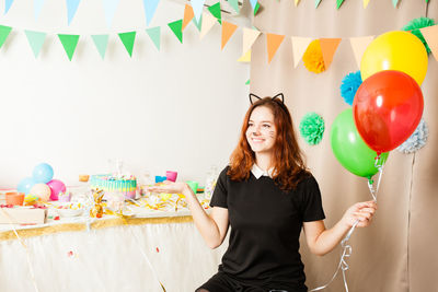 Portrait of smiling woman standing with balloons