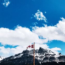 Low angle view of flag on snowcapped mountain against sky