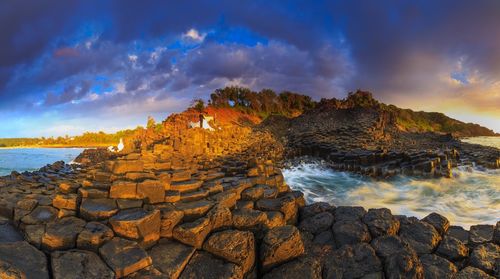 Rocks on shore against sky during sunset