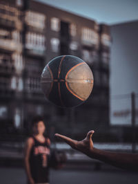 Cropped image of man with ball against building in city