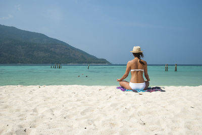 Rear view of a woman meditating on beach