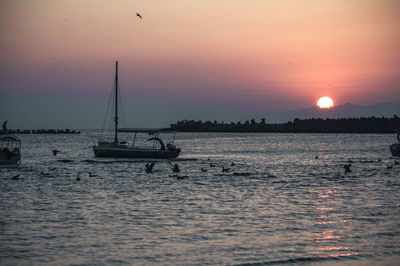 Silhouette sailboats in sea against sky during sunset