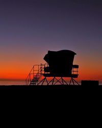 Silhouette lifeguard hut against clear sky during sunset