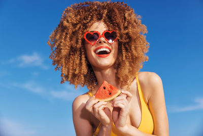 Low angle view of woman wearing sunglasses against sky