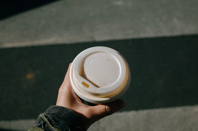 High angle view of hand holding coffee cup