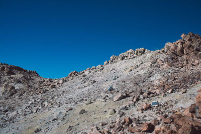 Low angle view of rocky mountains against clear blue sky