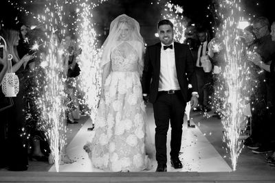 People standing by illuminated street light at night