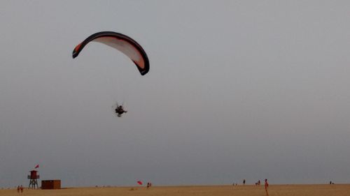 Person paragliding over sea against sky